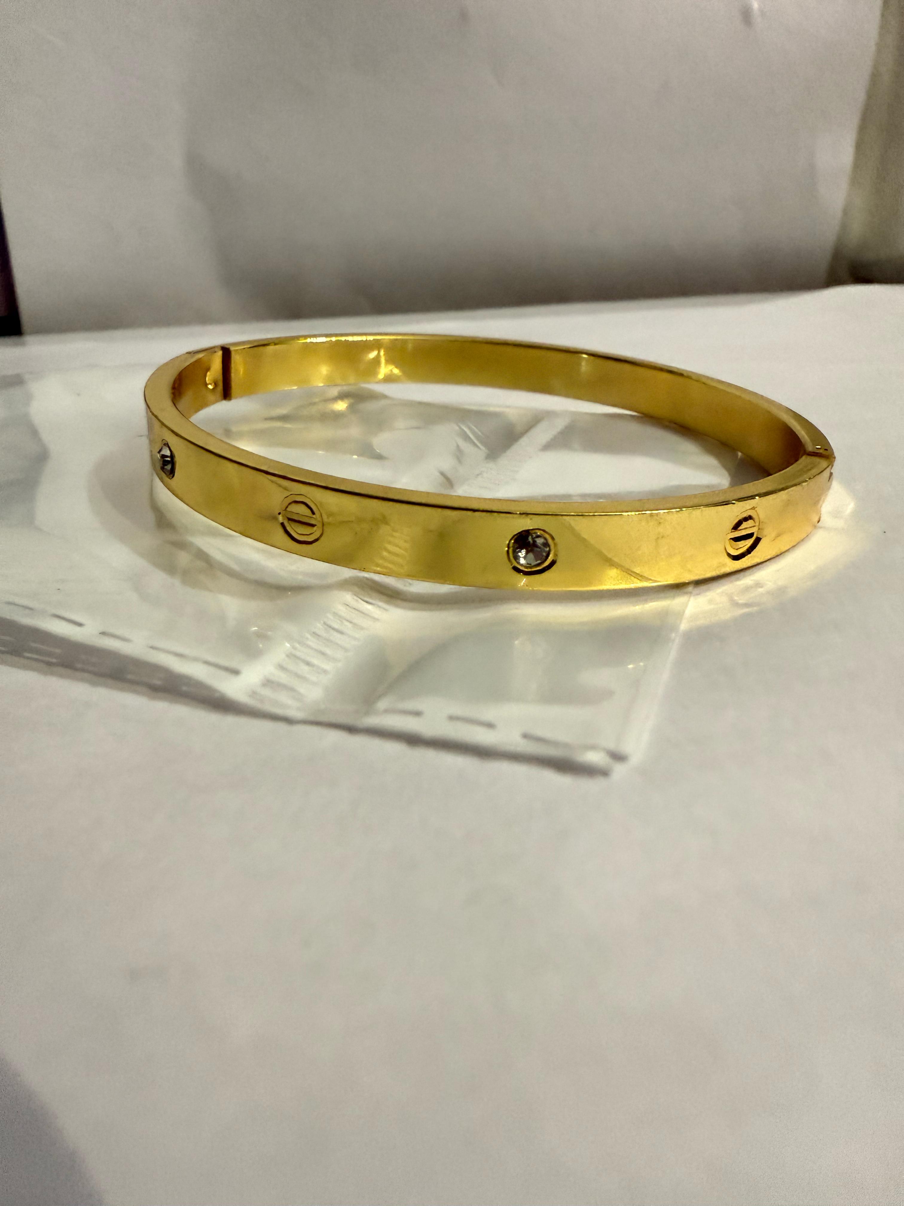 Elegance in Simplicity: A Gold-Toned Bangle Bracelet with Diamond Accents
